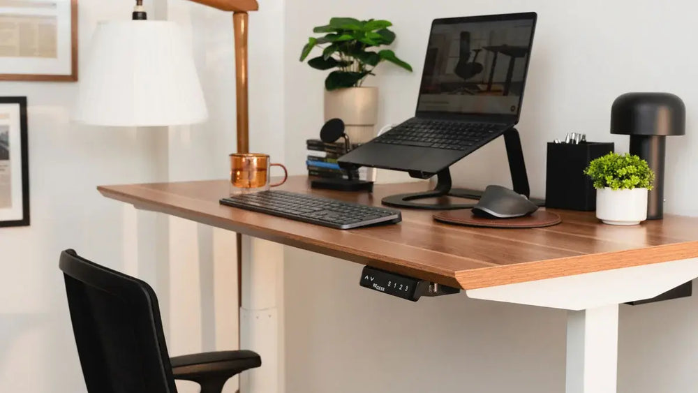 Small home office setup with a compact standing desk, laptop stand, monitor, keyboard and ergonomic workspace in a limited space.