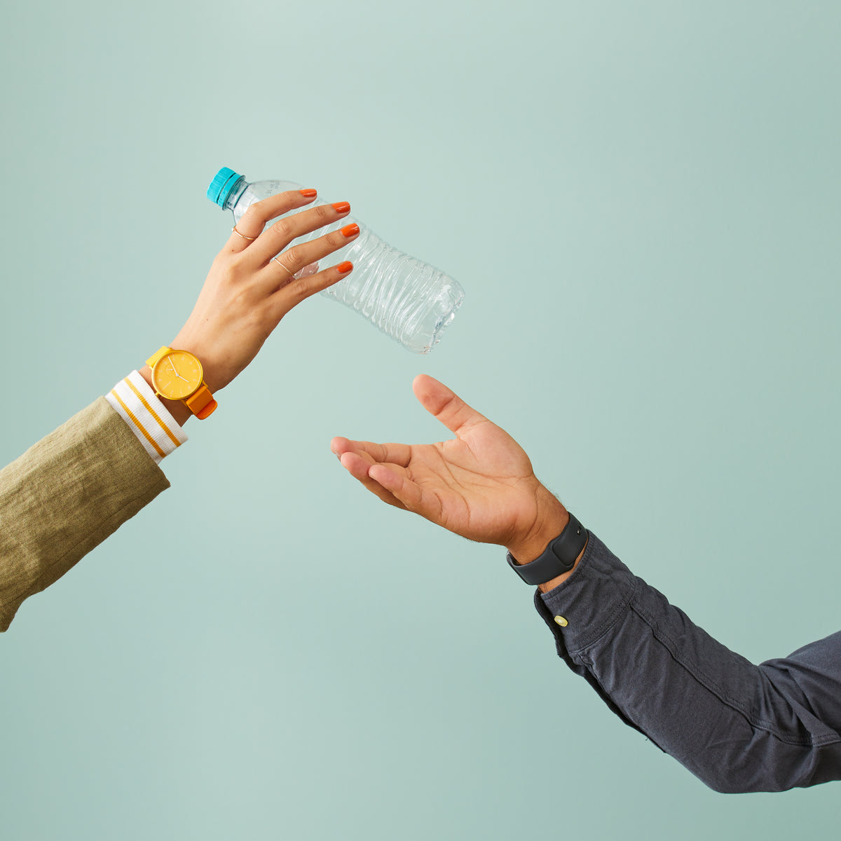 Hands passing an empty plastic bottle, symbolising the use of recycled materials and sustainable manufacturing practices